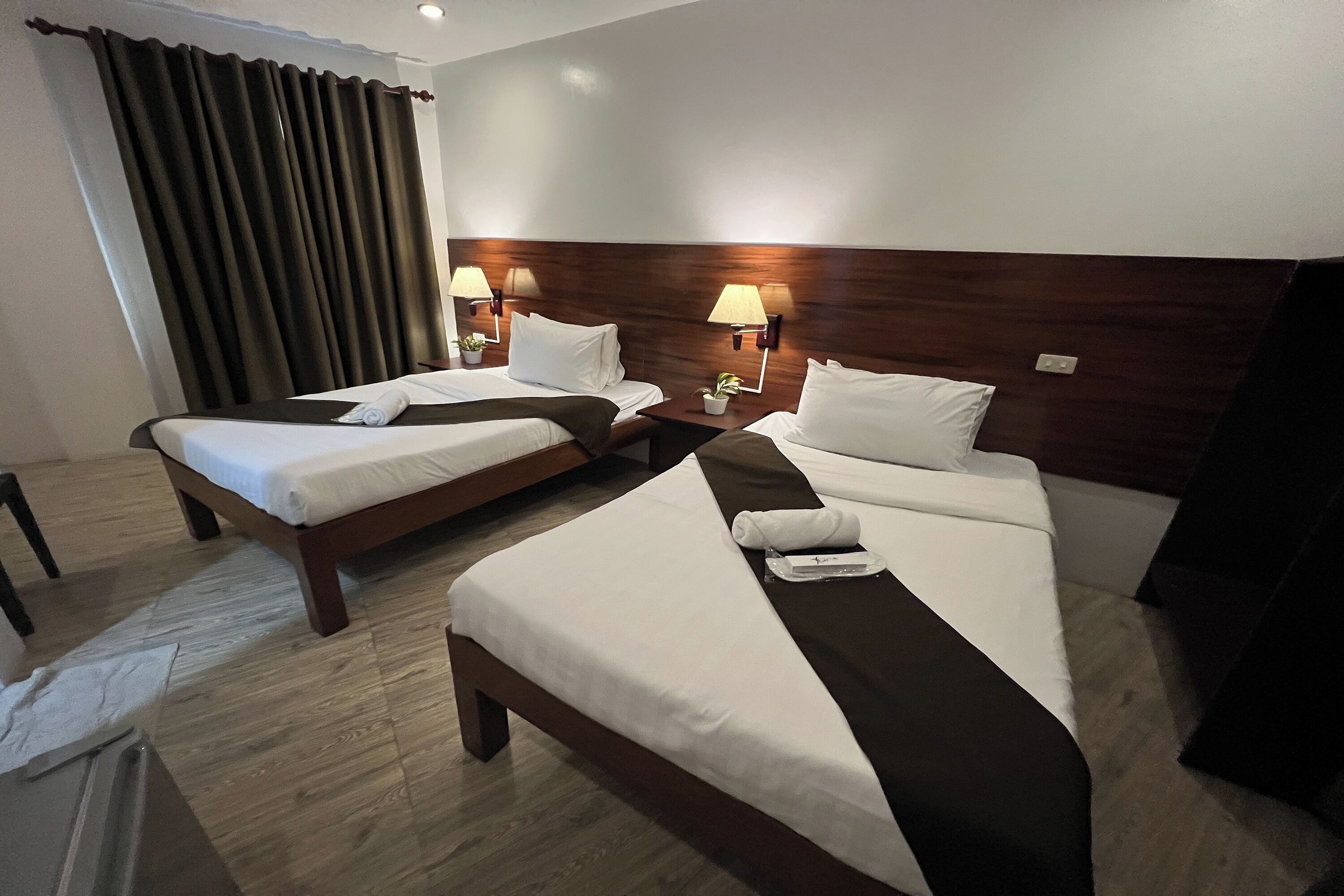 Ein Hotelzimmer mit zwei Betten, Holz-Kopfteilen, weißen Bettwäsche und Nachttischlampen.