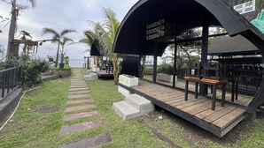 Un espacio de estar techado al aire libre con una terraza de madera y escalones que llevan a una plataforma.