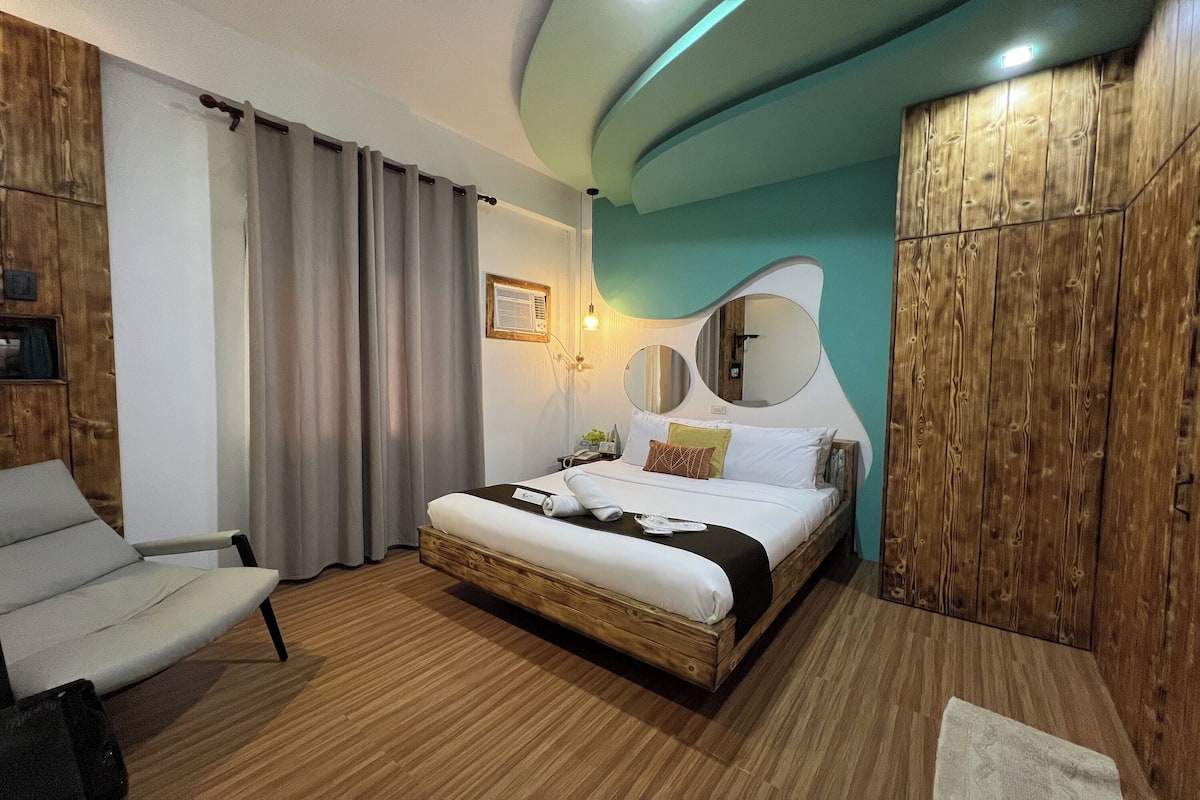 A modern bedroom with a wooden bed, a sofa, and a wardrobe.