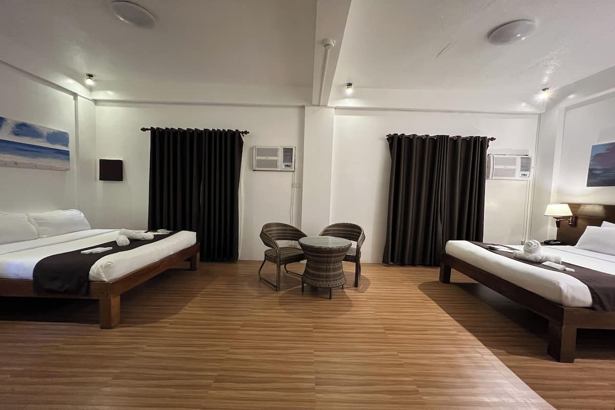 A hotel room with two beds, a small round table with chairs, and two air conditioning units.