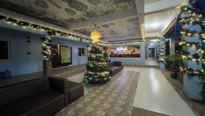 Un hall con un árbol de Navidad, zonas de estar y un techo decorado con motivos vegetales.