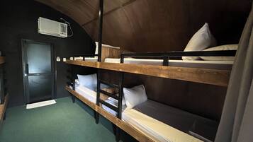 A bunk room with two bunk beds, a wooden ceiling, and a door.