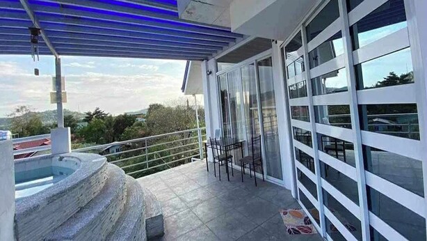 Ein Balkon mit Glastür, Whirlpool und Blick auf die umliegende Landschaft.