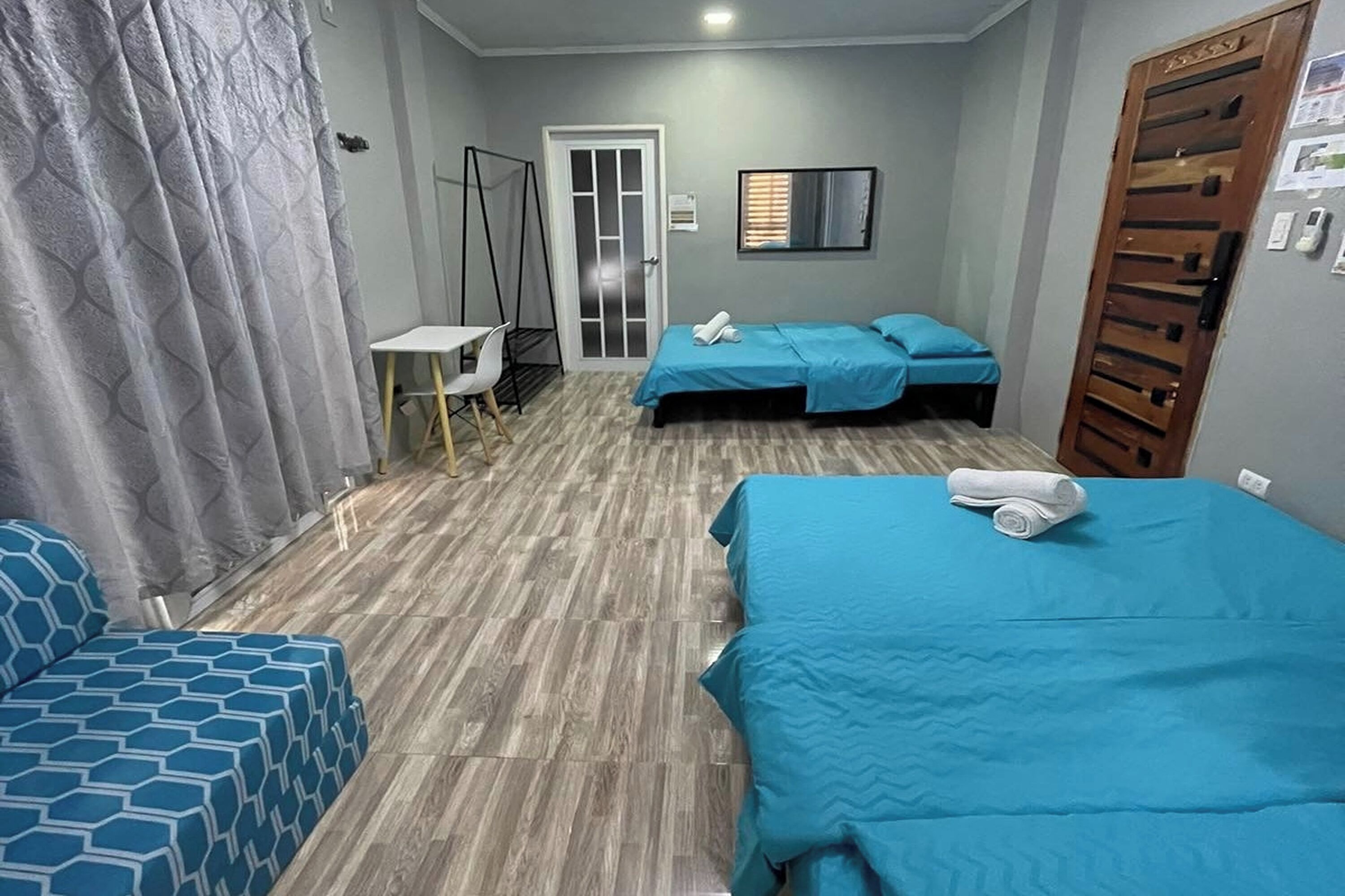 Habitación de hotel con dos camas, un escritorio, una silla y un armario.