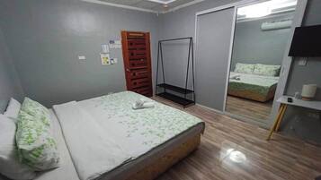A bedroom with a bed, a wardrobe, a mirror, and a television.