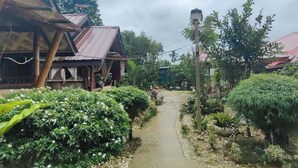 Un sendero estrecho bordeado de exuberante vegetación y edificios de madera tradicionales.