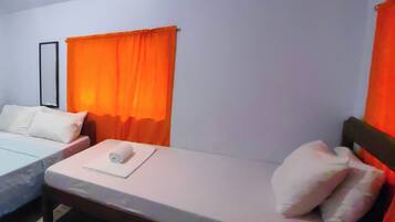 Een hotelkamer met twee eenpersoonsbedden, elk met wit beddengoed en kussens, en een oranje gordijn.