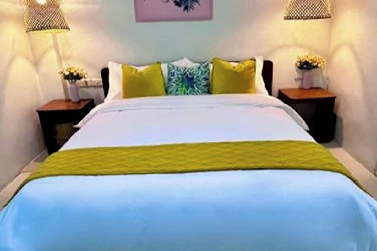 A bed with a white and yellow bedspread, two nightstands with lamps, and a wall with a framed picture.