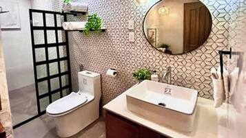 A modern bathroom with a freestanding toilet, a sink with a mirror above it, and a patterned wall.