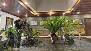 Un vestíbulo amplio con fuente de agua, plantas en macetas y obras de arte en las paredes.