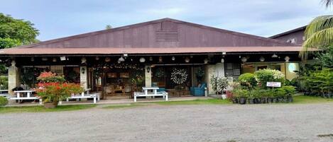 A building with a covered porch, outdoor seating, and potted plants.