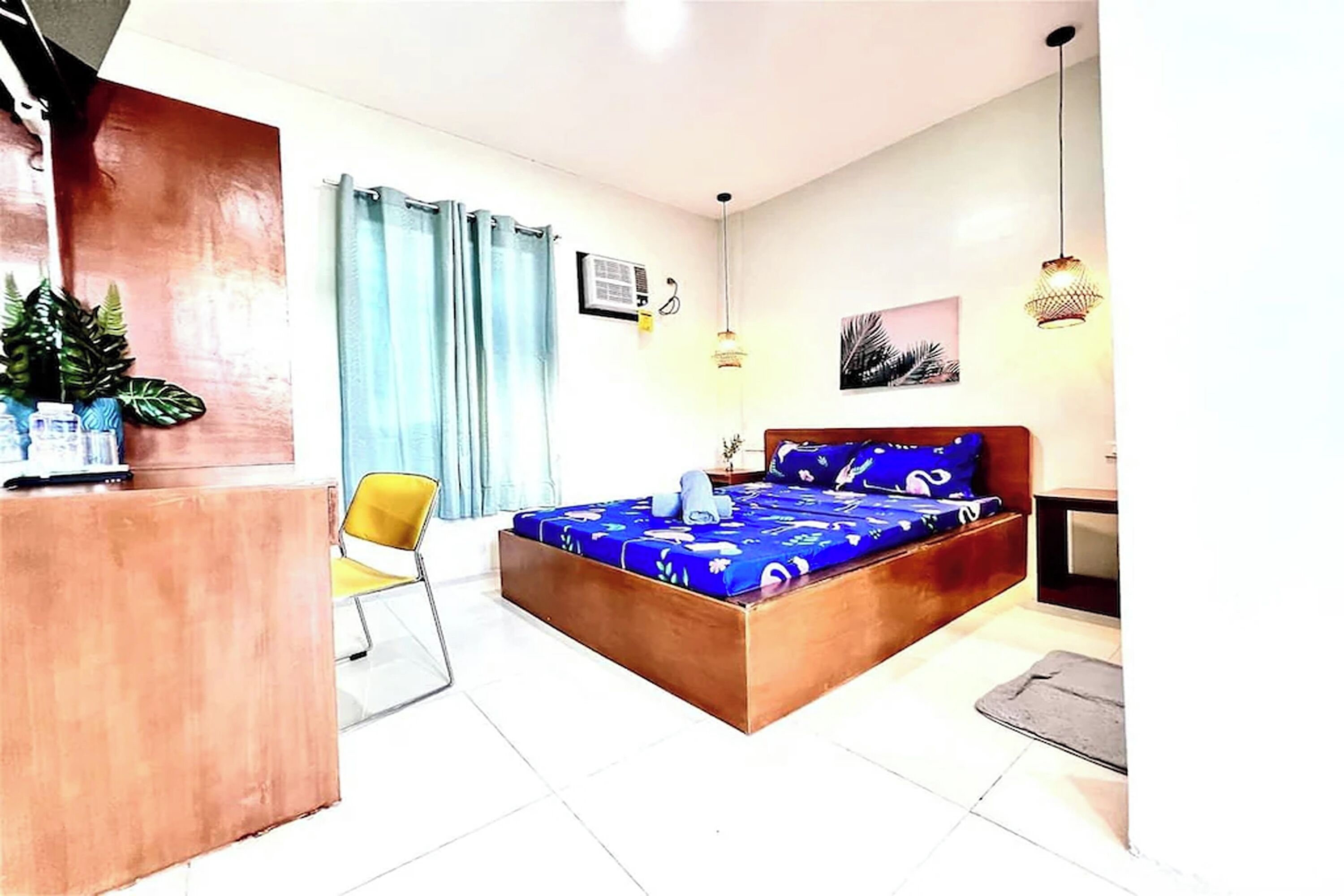 A bedroom with a bed, a desk, a chair, and a small table.