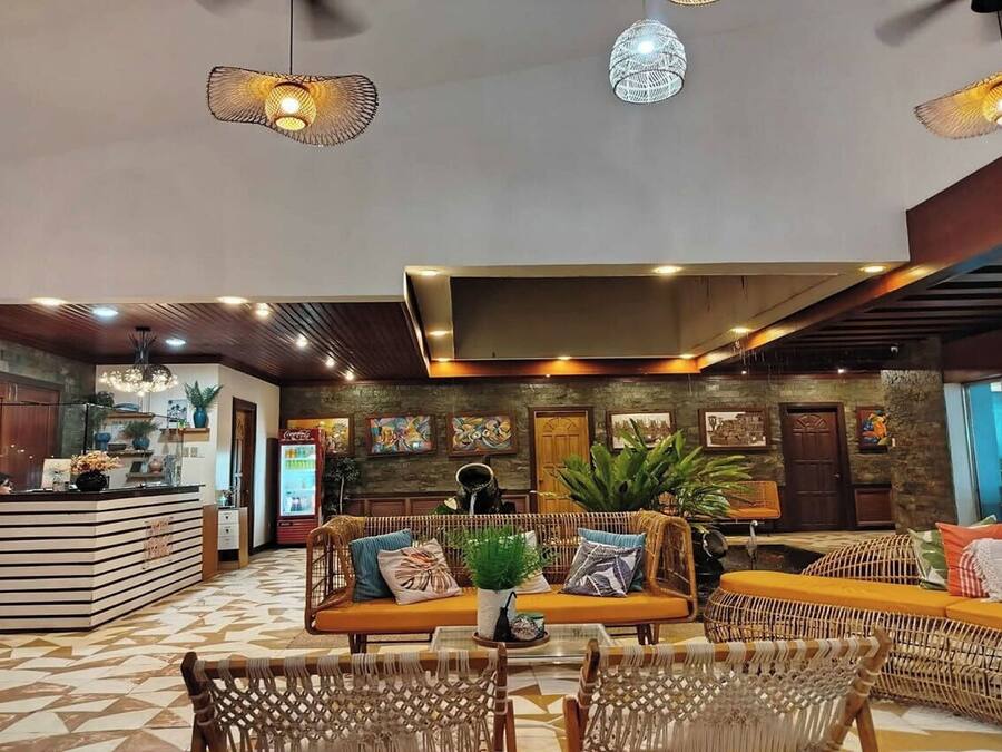 A spacious lobby with a reception desk, seating area, and a large plant centerpiece.