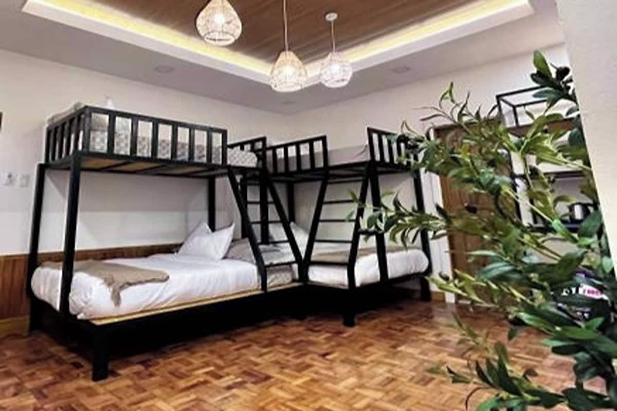 A bunk bed room with wooden flooring and a hanging light fixture.
