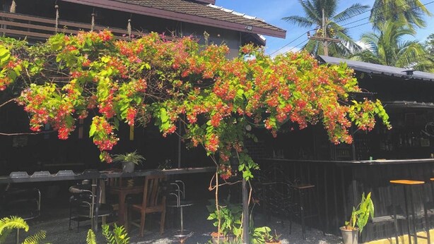 A traditional building with a tiled roof and a lush garden with flowering plants. - Blockhouse Samui (Koh Samui)