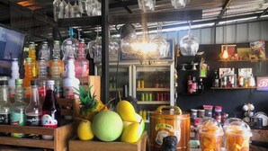 A bar area with a variety of bottles, a fruit display, and a dog figurine. - Blockhouse Samui (Koh Samui)