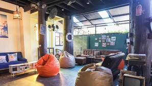 A cozy living room with a blue sofa, two bean bags, a brown couch, and a vintage TV. - Blockhouse Samui (Koh Samui)