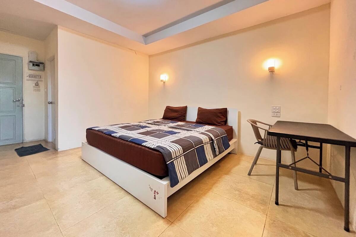 A bedroom with a bed, a desk, and two wall-mounted lights.
