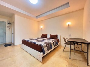 Un dormitorio con cama, escritorio y dos luces fijadas a la pared.