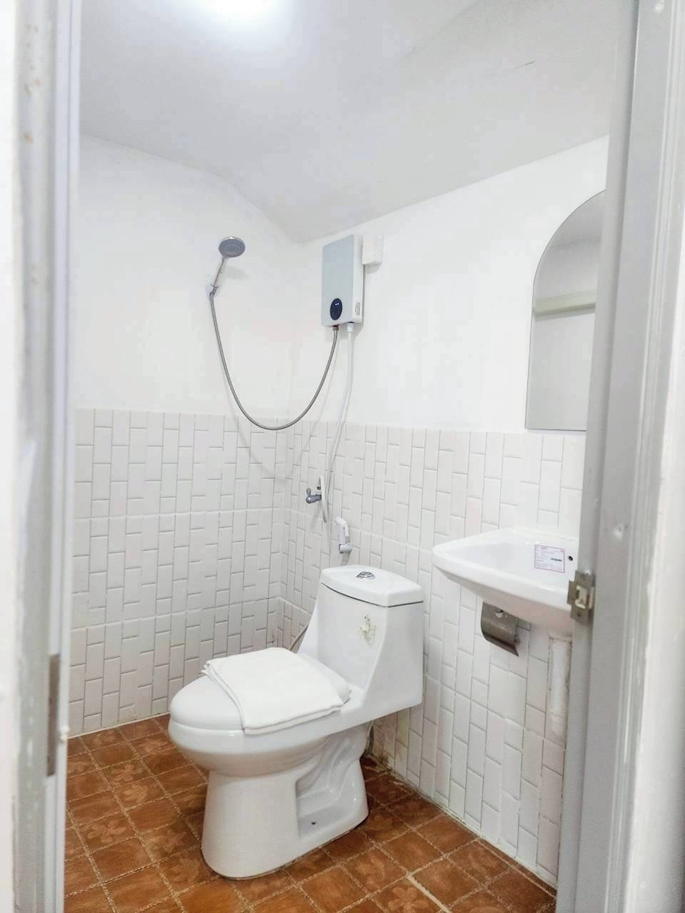 A small bathroom with a toilet, a shower, and a sink.