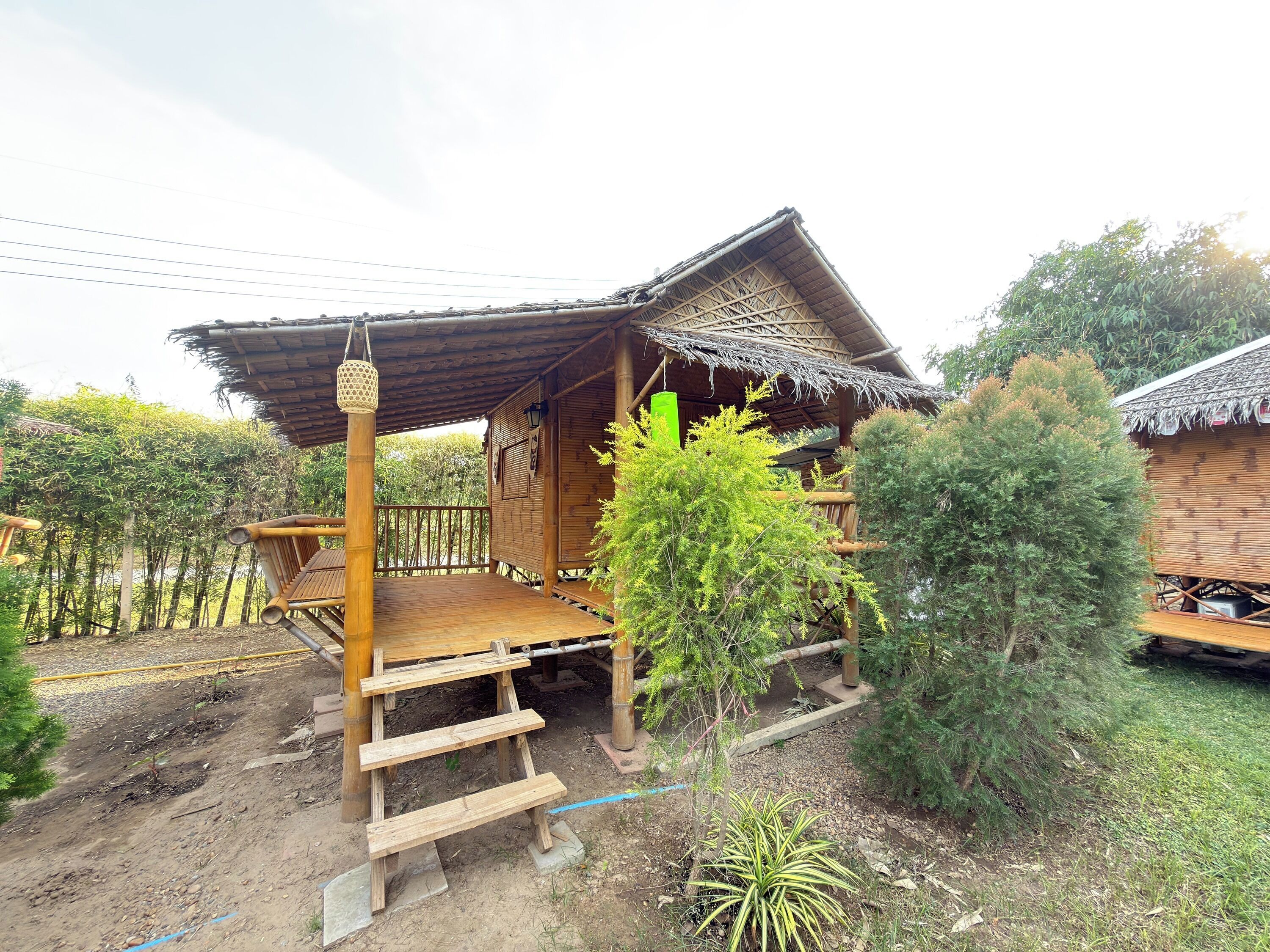 A wooden cabin with a thatched roof, a wooden deck, and a small staircase leading to a porch.