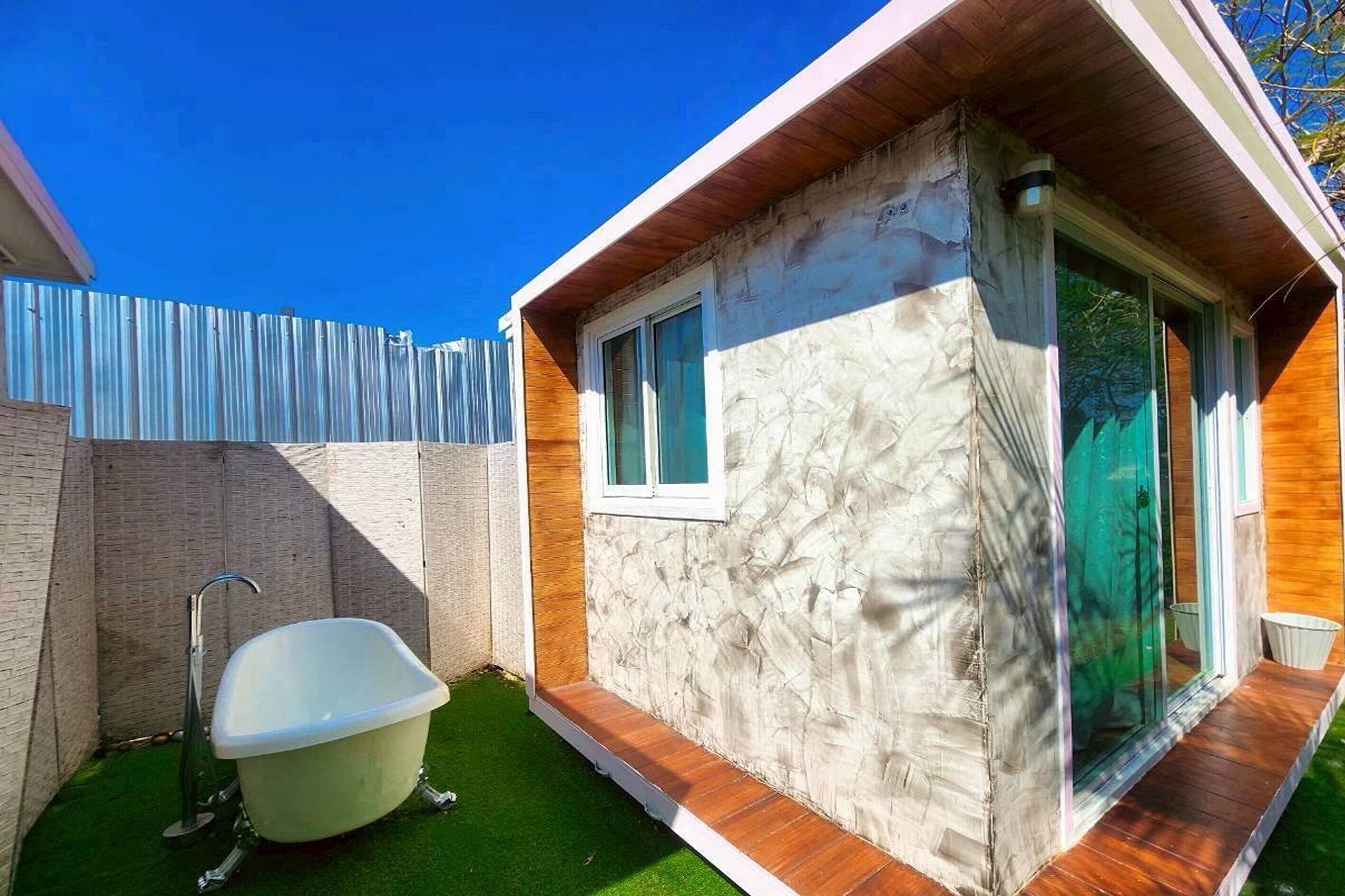 A modern house with a bathroom featuring a freestanding bathtub, a window, and a door leading to a covered outdoor area.