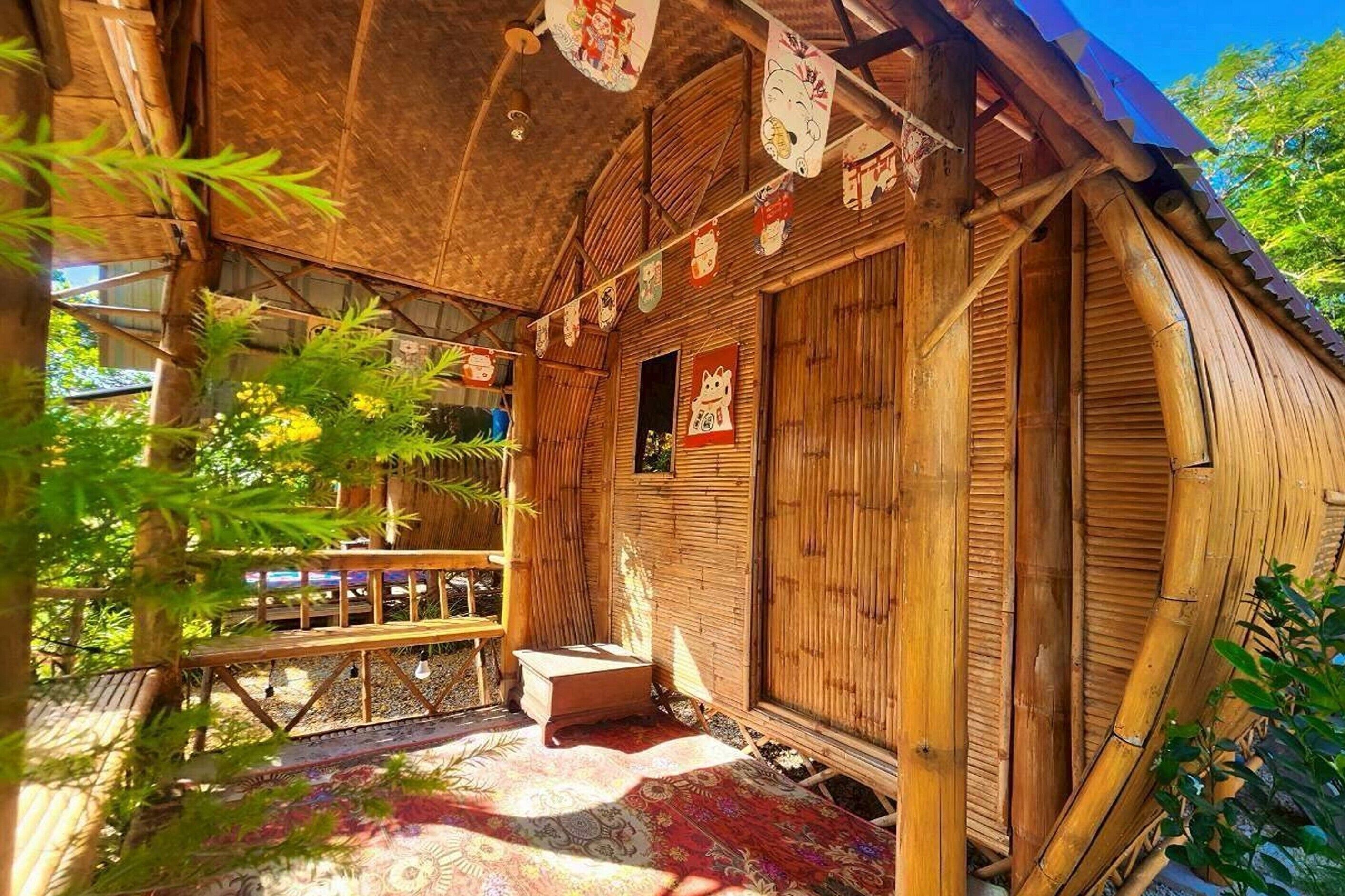 A traditional wooden building with a covered porch, bamboo decorations, and a small table.