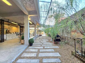 An indoor courtyard with a stone pathway, seating areas, and a cafe. - Nap & Nomad Hostel Tha Phae Gate (Chiang Mai)