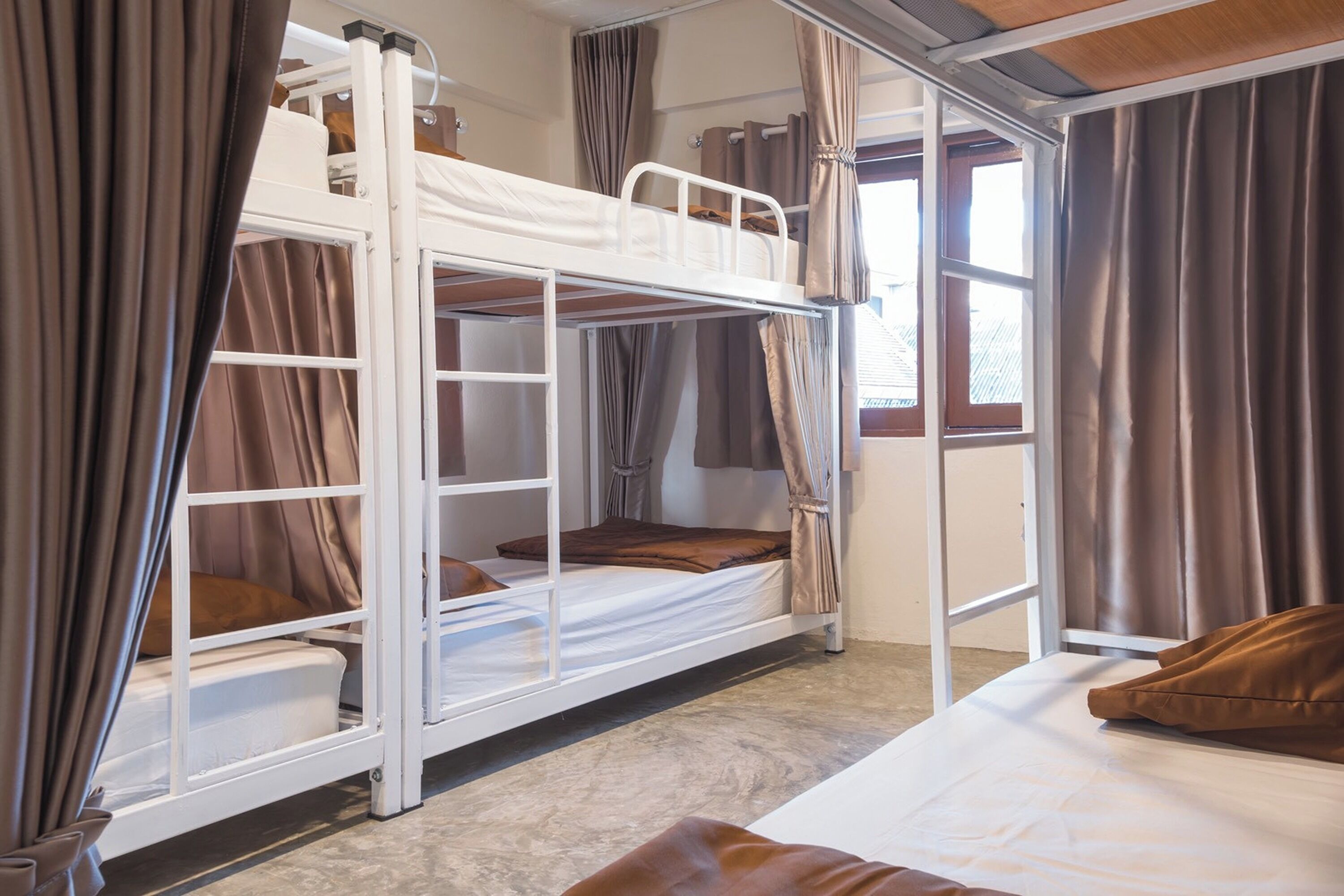 Habitación con literas, cortinas, una ventana y una cama con almohada.