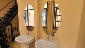 Une salle de bain avec deux lavabos, un miroir et un escalier.
