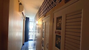 Un couloir avec des portes, un appareil de climatisation et un plafond à motifs.