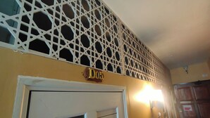 Une pièce avec une porte blanche, un plafond décoratif orné d’un motif géométrique et une enseigne au-dessus de la porte sur laquelle on peut lire « Do5 ».