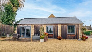 A single-story building with a stone facade, a tiled roof, and a gravel driveway. - Beautiful 2 Bedroom Barn in Cerney Wick (Cerney Wick)