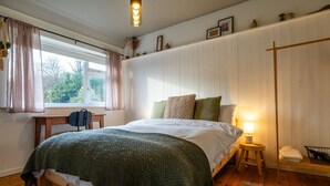 Une chambre confortable avec un lit en bois, un bureau et une fenêtre avec des rideaux.