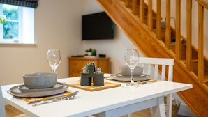 A dining table set with plates, bowls, cutlery, and glasses, with a wooden staircase in the background. - The Alehouse Retreat, The Crown Inn (Cerney Wick)