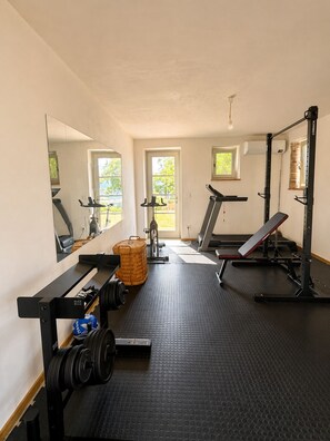 A gym with exercise equipment, a bench, a mirror, and a window.