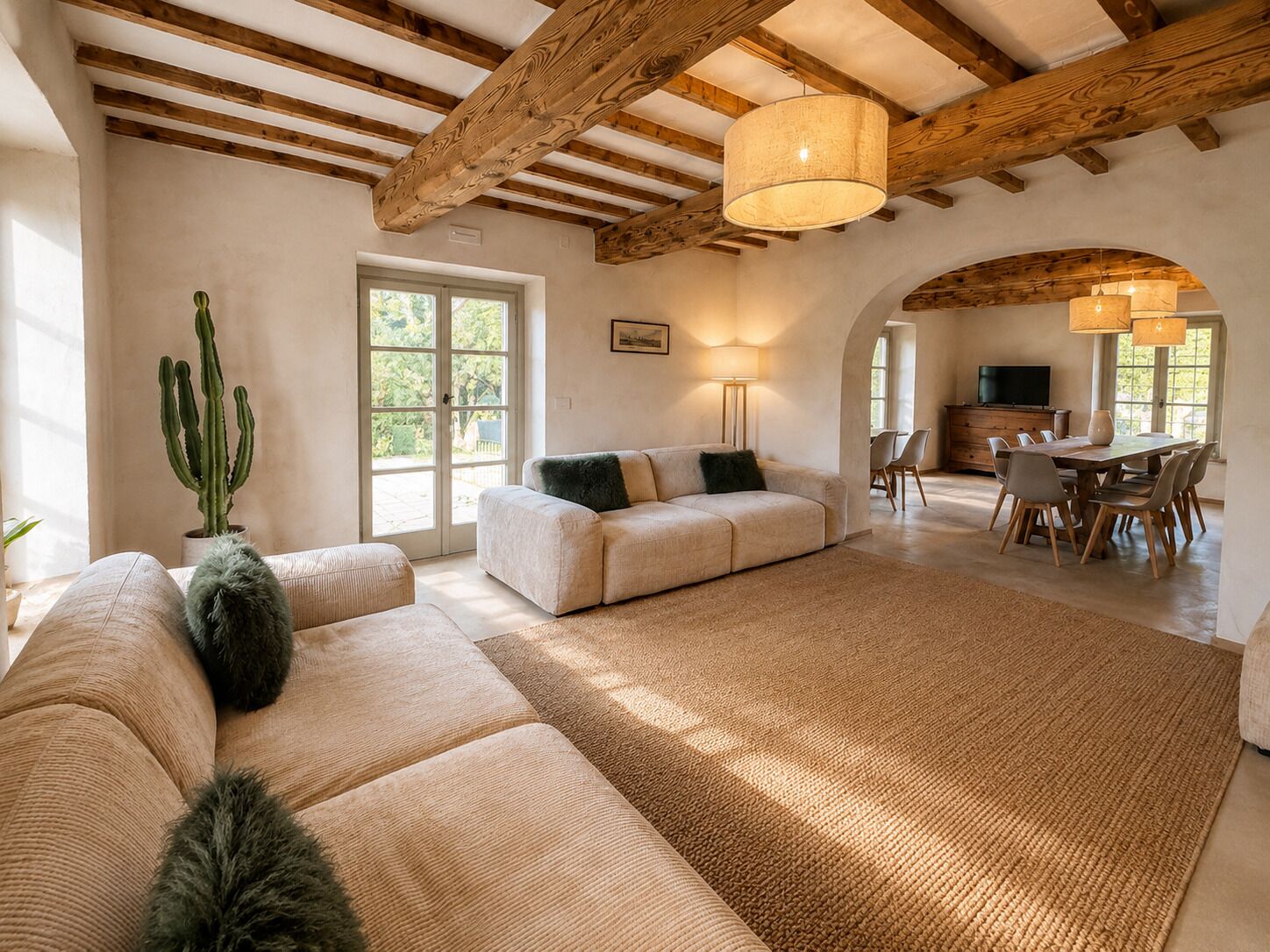 Un'ampia zona giorno con soffitto alto, una sala da pranzo e una pianta di cactus.
