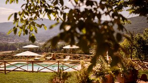 Zona de piscina con sombrillas, sillones de descanso y vistas al paisaje.