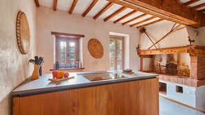 A kitchen with a wooden island, a brick oven, and a window with a view. - Tenuta Seriole (Poppi)