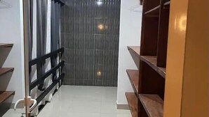 A hallway with a mirrored closet door, a wooden bench, and a tiled floor. - thiego'sapparthotel (Lomé)