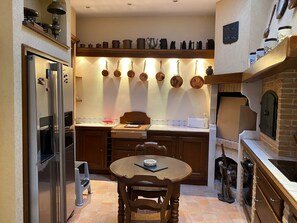 Eine kleine Küche mit Kühlschrank, Herd und einem Esstisch mit Stühlen.