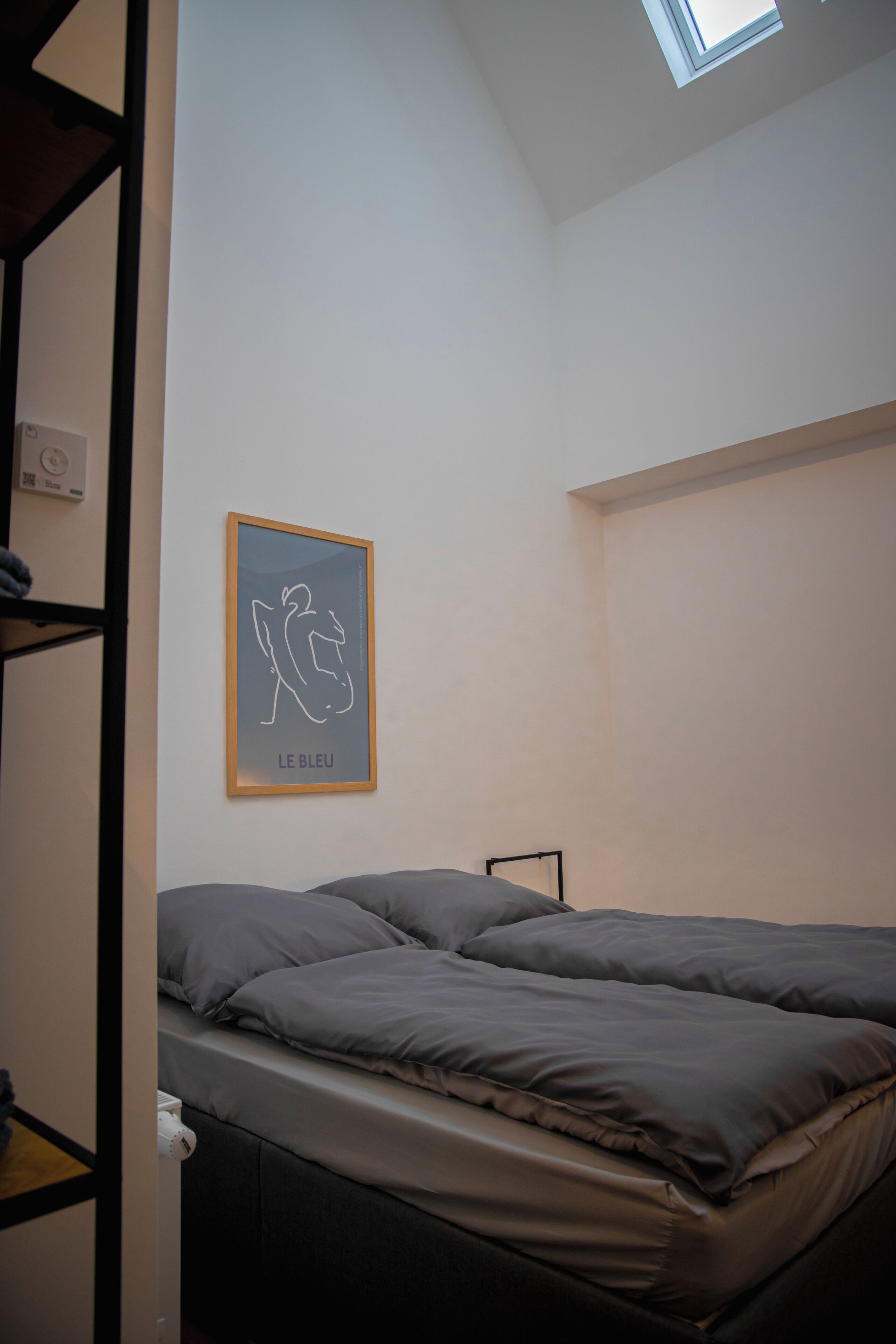 Een slaapkamer met een stapelbed, dakraam en een gekaderd kunstwerk aan de muur.