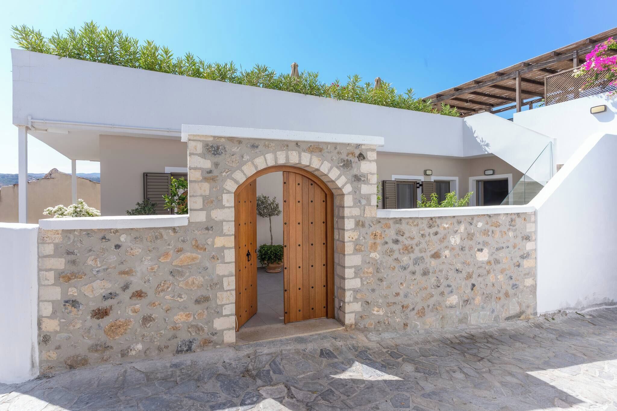 Un edificio moderno con fachada de piedra, puerta de madera y un pequeño jardín.