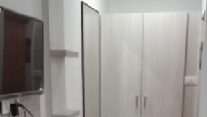 A modern room with a flat-screen TV mounted on the wall, a white wardrobe, and a red bucket on the floor. - J Residency (Pochampalli)
