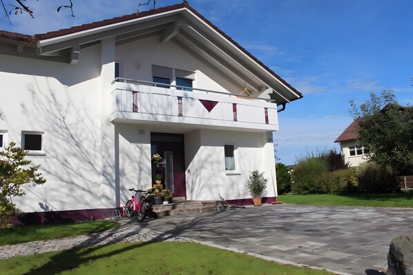 Ein zweistöckiges Haus mit Balkon, gepflasterter Auffahrt und Garten.