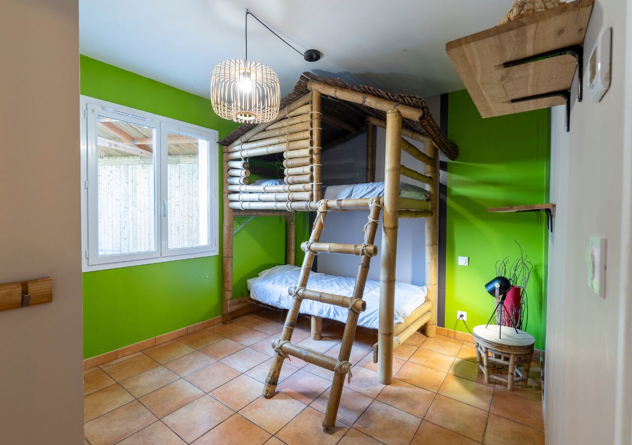 Una habitación con una cama individual superpuesta, una escalera, una mesita pequeña y una lámpara colgante.