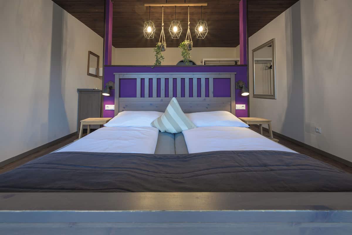 A modern bedroom with a large bed, a wooden headboard, and pendant lighting.