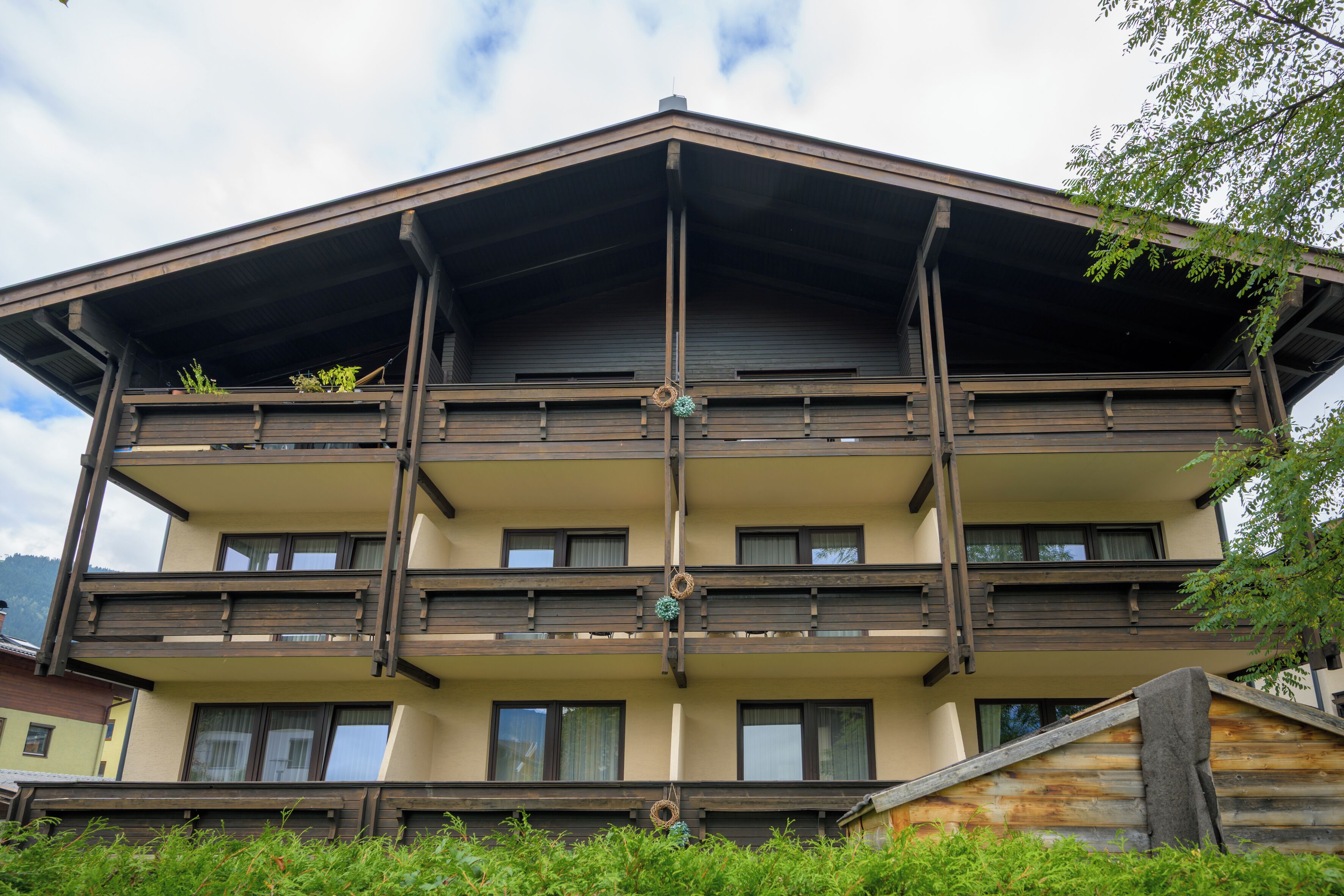 Un edificio de varios pisos con balcones, barandillas de madera y una columna central.