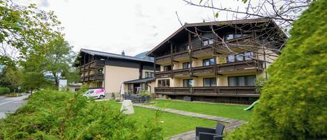 Un immeuble à plusieurs étages doté de balcons, d’un espace extérieur couvert et d’une pelouse verdoyante.