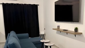 Una sala de estar moderna con un sofá modular, un televisor de pantalla plana montado en la pared y una mesita de centro.